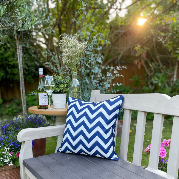 Blue & White Waterproof Outdoor Garden Cushion with a Striped Chevron Design on a Garden Bench with Flowers and Fruit